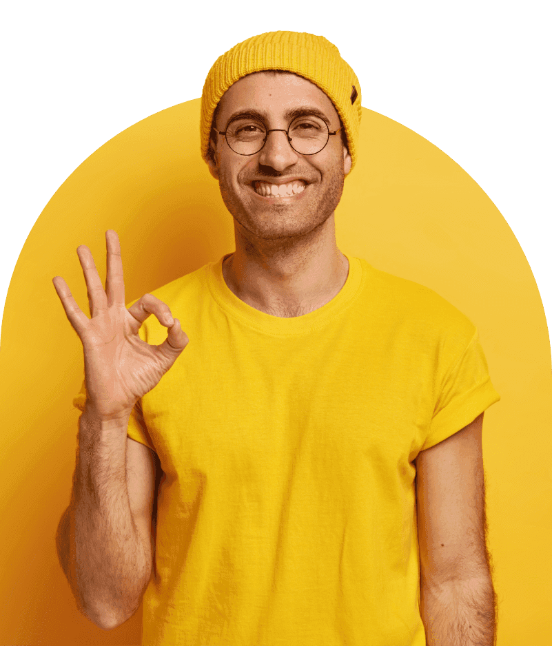 Smiling man in a yellow beanie and t-shirt making an OK gesture